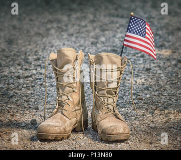 Il vecchio militare stivali da combattimento con la bandiera americana. Ghiaia rocciosa dello sfondo. Il Memorial Day o giorno dei veterani del concetto. Foto Stock