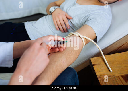 Medico donna prendendo un sangue dal paziente di sesso maschile nella clinica privata Foto Stock