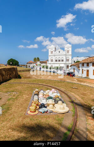 Cappelli stabiliti esposti per la vendita ai turisti sulla Forte Galle bastioni dal bianco iconico Meeran Moschea Jumma, Galle, sud della provincia, Sri Lanka Foto Stock