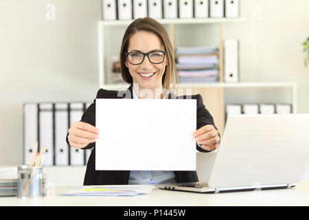 Felice executive che mostra una carta bianca alla fotocamera in ufficio Foto Stock