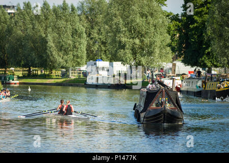 Un narrowboat passa i canottieri lungo il fiume Cam in un assolato pomeriggio estivo, Cambridge, Regno Unito Foto Stock