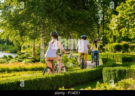 Gente in bicicletta, vista posteriore. Giovani amici in appoggio all'aperto. Persone e uno stile di vita sano. Foto Stock