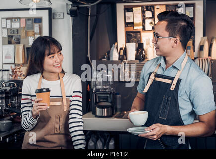 Due barista parlare insieme circa assaggiato della tazza di caffè con felice commozione al bancone bar presso il cafe.coffee shop business concetto proprietario,servizio mente attendere Foto Stock