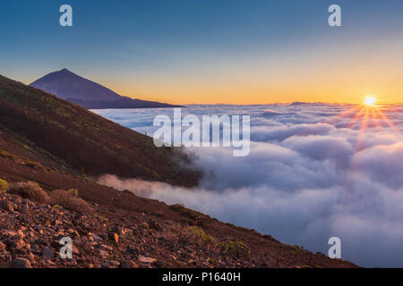 Lo spettacolo del sole che tramonta tra le nuvole.Tramonto nel vulcano Teide national park. Foto Stock