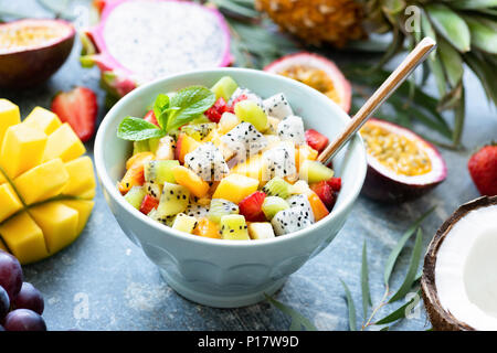 Macedonia di frutta con frutta tropicale mango, cocco, pitaya in una ciotola. Thai vacanze estate cibo vegan. Concetto di stile di vita sano, mangiare sano, veget Foto Stock