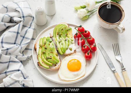 La prima colazione con avocado toast, uova e caffè. Una sana prima colazione, uno stile di vita sano concetto Foto Stock