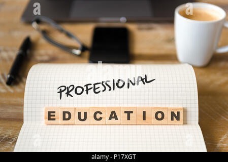 Primo piano su notebook sulla scrivania vintage superficie, di fronte a fuoco sui blocchi di legno con lettere che la formazione professionale il testo. Foto Stock
