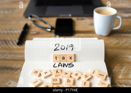 Primo piano su notebook sulla scrivania vintage superficie, di fronte a fuoco sui blocchi di legno con lettere che 2019 leggi fiscali testo. Foto Stock