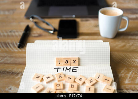 Primo piano su notebook sulla scrivania vintage superficie, di fronte a fuoco sui blocchi di legno con lettere che imposta il testo del tempo. Foto Stock