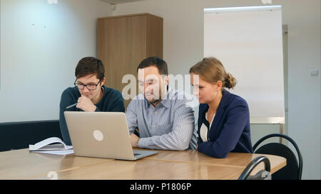 Il gruppo di allegro positivo gli studenti utilizzando laptop e studiare insieme in aula Foto Stock