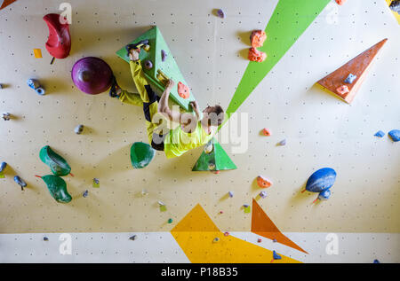 Giovane uomo climbing bouldering percorso. In piscina palestra di arrampicata. Foto Stock