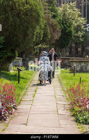 Una signora anziana arriva per un matrimonio presso la chiesa di Santa Maria Vergine e di santa Maria Maddalena a Tetbury. Essa spinge e uomo anziano in una sedia a rotelle, GLOUCESTERSHIRE REGNO UNITO Foto Stock