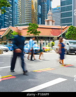 Le persone che attraversano una strada a Singapore il centro business. Sfocatura del movimento Foto Stock