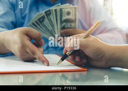 Offerta uomo lotto di centinaia di fatture del dollaro. Close up di business man firma contratto facendo una trattativa, business i dettagli del contratto. Foto Stock