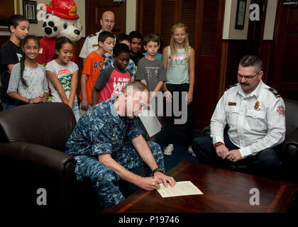 161005-N-YD204-008 NAVAL AIR FACILITY Atsugi, Giappone (ott. 5, 2016) - Naval Air Facility (NAF) Atsugi Comandante Capt. John Bushey segni una prevenzione incendi proclamazione presso il suo ufficio con studenti provenienti da Shirley Lanham scuola elementare. Bushey firmato la proclamazione dichiarando la settimana di ottobre 4-10, 2016 per essere la prevenzione degli incendi settimana in tutto il NAF Atsugi. (U.S. Foto di Marina Sottufficiali di terza classe Matteo C. Duncker/rilasciato) Foto Stock