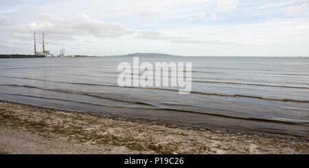 La penisola di Howth e landmark twin camini di Poolbeg Power Station in piedi sopra la baia di Dublino come visto da Sandymount. Foto Stock