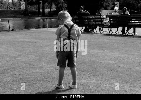 Triste giovane ragazzo in piedi da solo in shorts foto in bianco e nero Foto Stock