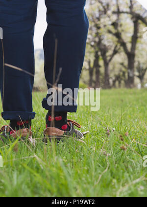 Close-up di uomo di gambe in eleganti sneakers su erba verde Foto Stock