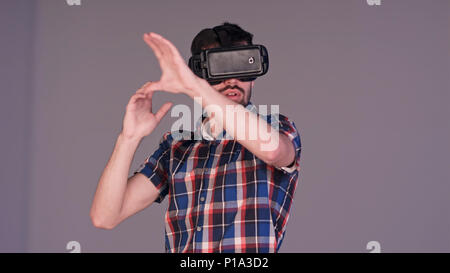 Eccitato giovane uomo in VR occhiali gestualità attivamente in aria Foto Stock