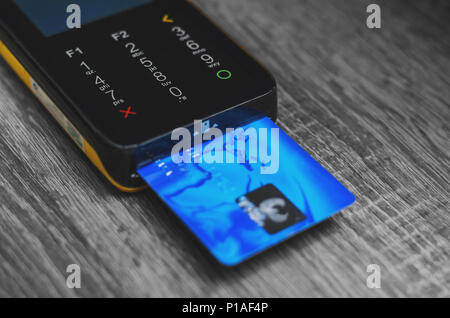 Lettore di carte di credito con un blu carta di credito inserita. Terminale carte di credito con touch screen. Foto Stock