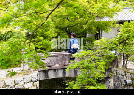 Una Donna vestita come una Geisha seduta tranquillamente nei giardini di Kiyomizu-dera tempio, Kyoto, Giappone. Foto Stock