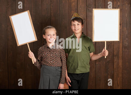 I bambini sono vestiti in retrò uniformi militari. Si stanno tenendo i poster in bianco per i veterani dei ritratti. Foto Stock