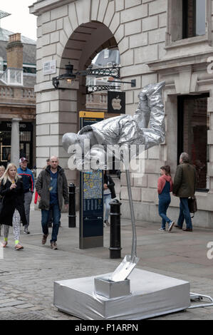 L'artista di strada dipinta in argento fisico di eseguire la magia di Covent Garden Square su James Street nella City of Westminster, Londra, Inghilterra, Regno Unito Foto Stock