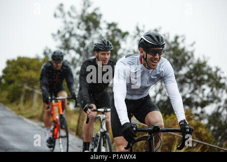 Sorridente ciclista maschio escursioni in bicicletta con gli amici Foto Stock