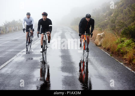 I ciclisti di sesso maschile ciclismo su strada bagnata Foto Stock