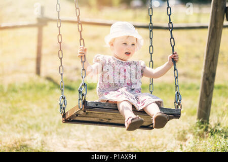 Carino bambina divertendosi su altalena per esterno Foto Stock