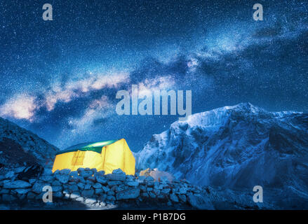 Via Lattea, giallo incandescente tenda e montagne. Incredibile scena con montagna himalayana, blu cielo stellato di notte in Nepal. Rocce con picco innevato e cielo Foto Stock