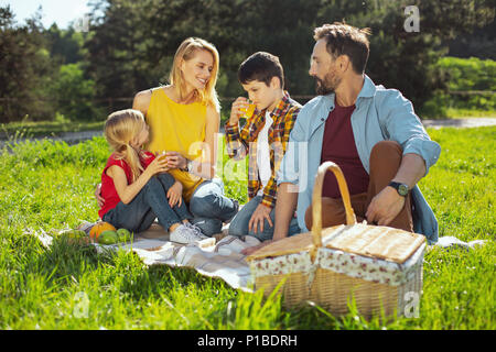 Cura i genitori avente un picnic con i loro bambini Foto Stock