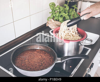 Persona che serve pasta e ragù alla bolognese sulla stufa Foto Stock