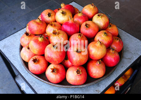 Piatto di rosa e rosso melagrane per la vendita su un mercato della frutta Foto Stock