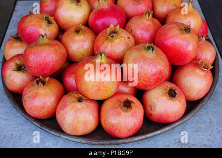 Piatto di rosa e rosso melagrane per la vendita su un mercato della frutta Foto Stock