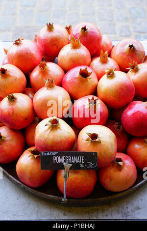 Piatto di rosa e rosso melagrane per la vendita su un mercato della frutta Foto Stock
