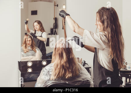 Stilista di sesso femminile di applicare un colorante per i client capelli al salone di bellezza Foto Stock