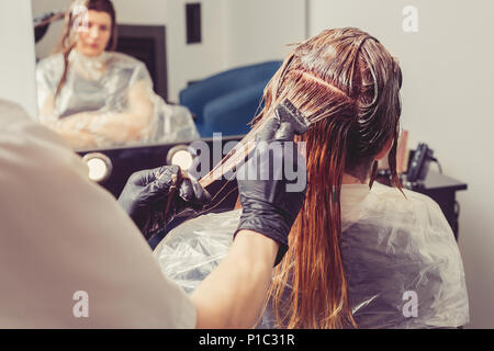 Stilista di sesso femminile di applicare un colorante per i client capelli al salone di bellezza Foto Stock