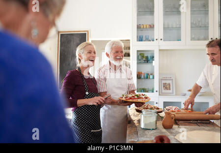 Coppia senior rendendo la pizza in classe di cucina Foto Stock