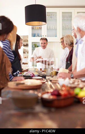 Senior amici ascolto di chef in pizza Cooking class Foto Stock