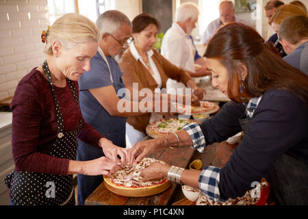 Le donne anziane amici rendendo la pizza in classe di cucina Foto Stock