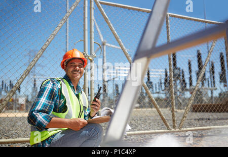 Ritratto sorridente e fiducioso ingegnere maschio con un walkie-talkie all impianto di alimentazione Foto Stock