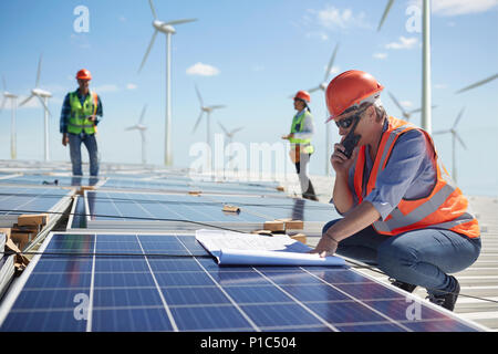 Ingegnere con i walkie-talkie e blueprint al pannello solare a sunny impianto di alimentazione Foto Stock