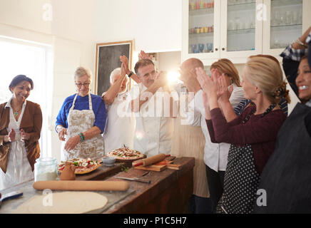 Chef e attiva gli amici senior battendo le mani in pizza Cooking class Foto Stock