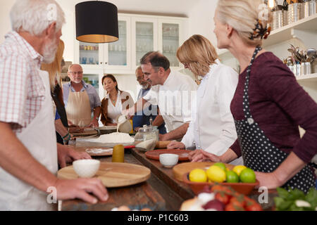 Senior attiva gli amici a guardare lo chef in pizza Cooking class Foto Stock