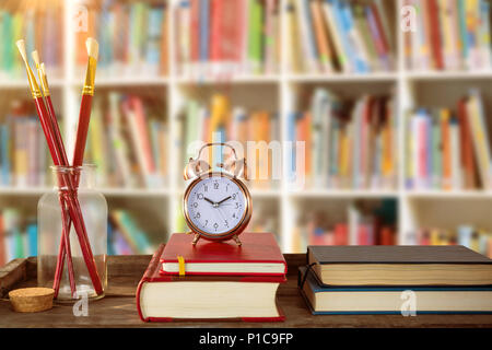 Immagine composita di libri con la sveglia con libri e pennelli sulla tavola di legno Foto Stock