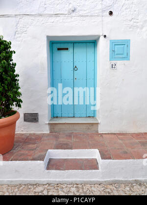 Un blu turchese porta in un dipinto di bianco villaggio andaluso nella Sierra de Tejeda. Foto Stock