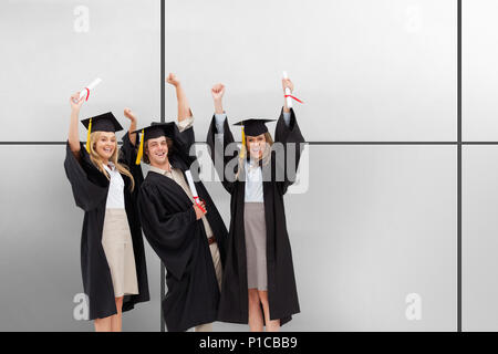 Immagine composita di tre studenti di laurearsi robe alzando le braccia Foto Stock