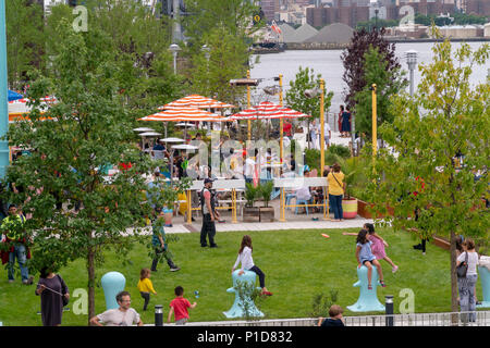 Nonostante il tempo inclemente di migliaia di visitatori accorsi per la grande apertura di Domino Parco nel quartiere di Williamsburg di Brooklyn a New York Domenica, 10 giugno 2018. Occupa il sito del Domino Sugar Co. raffineria, chiusa nel 2004, cinque acri di greenspace ha caratteristiche di acqua, scivoli, una passerella elevata, un Danny Meyer stand alimentari e pallavolo come pure molte altre dotazioni. Progettato da James Corner Field Operations, gli architetti dietro il design della linea alta, la raffineria di mattone di edificio, di cui una volta elaborato il 50 percento di tutto lo zucchero negli Stati uniti rimane per de Foto Stock