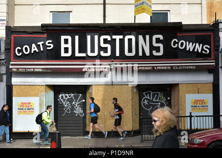La gente a piedi passato un intavolato e chiuso per donna fashion shop su Kentish Town Road. Negozi stanno chiudendo e la high street è in declino in quanto le persone Foto Stock